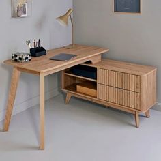 a wooden desk with drawers and a laptop on it in a room that has white walls