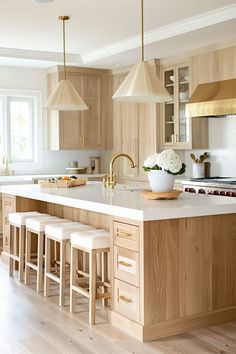 a large kitchen with wooden cabinets and white counter tops, along with bar stools