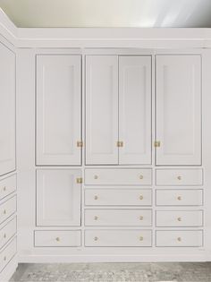 a large white closet with many drawers and gold knobs on the doors is shown