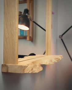 a wooden shelf with a light on it and a mirror in the backround