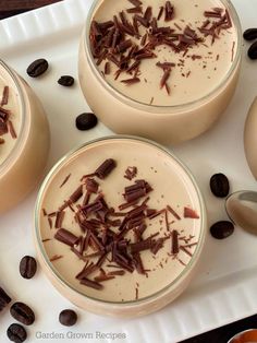 three desserts are sitting on a plate with coffee beans and chocolate shaving around them