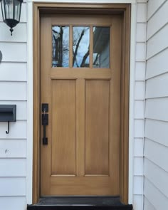 a wooden door on the side of a white house with a black mailbox in front