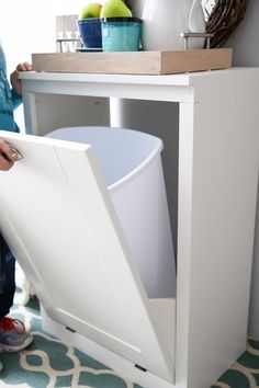 the bottom half of a white cabinet with an open door on it and a person standing next to it