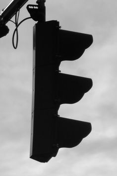 a black and white photo of a traffic light with the sky in the back ground