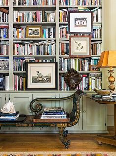 a room filled with lots of books on top of a shelf next to a lamp