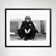 a black and white photo of a woman sitting on the ground with her hands crossed