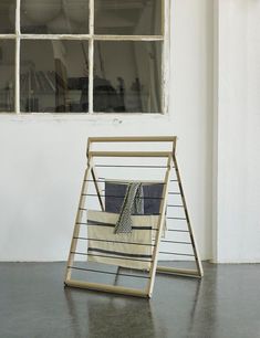 a chair sitting in front of a window next to a bag on top of a wooden stand