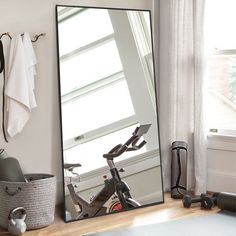 a mirror sitting on top of a wooden shelf next to a bike in front of a window