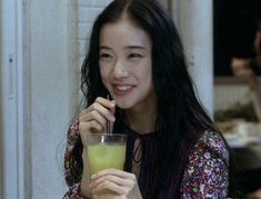 a woman sitting at a table with a drink in her hand