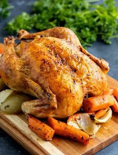 a roasted chicken with carrots and onions on a cutting board