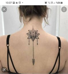 the back of a woman's neck with a flower and arrow tattoo on it