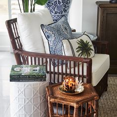 a wicker chair sitting next to a table with a candle on top of it