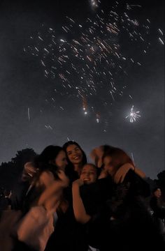 a group of people standing next to each other with fireworks in the sky