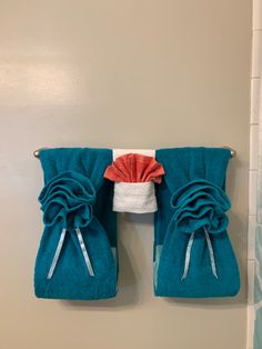 two blue towels hanging on the wall next to a towel rack with red and white ruffles