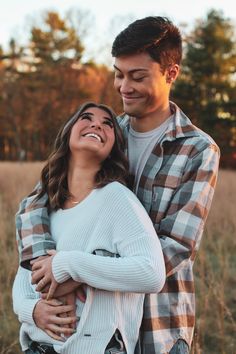 a young man and woman are hugging in a field