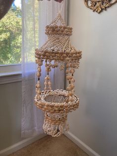 a bird feeder hanging from the side of a window in front of a white curtain