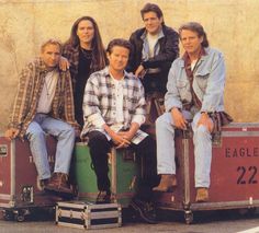 a group of people sitting next to each other in front of a wooden wall,