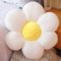 a white stuffed flower sitting on top of a bed