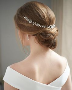 a woman wearing a wedding hair comb with pearls on the back of her head, looking off to the side