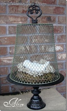 a bird in a cage sitting on top of a table next to a brick wall