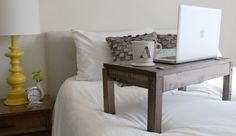 a laptop computer sitting on top of a wooden table next to a lamp and bed