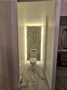 a white toilet sitting inside of a bathroom next to a doorway