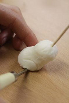 a person is cutting up some food on a wooden table with two small tongs