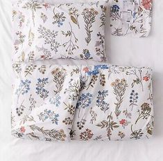 the bedding is made up with white sheets and floral designs on it, along with two pillows