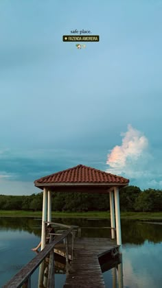 a wooden dock sitting on top of a lake under a blue sky with white clouds