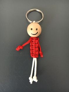 a red and white knitted keychain with a smiling man on it's face