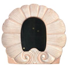 an ornate white frame with black glass in the shape of a shell, on a white background