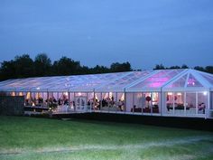 a large white tent set up for a party with people in it at night time