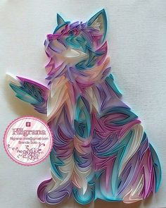 a paper cut out of a cat sitting on top of a white surface with a pink, blue and green design