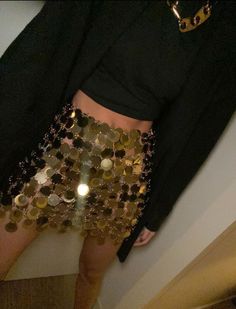 a woman in gold sequins is wearing a skirt and black jacket with her hands on her hips