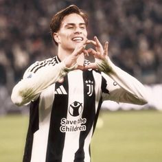 a man standing on top of a soccer field holding his hands up in the air