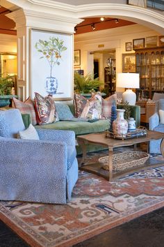 a living room filled with blue couches and pillows on top of a red rug