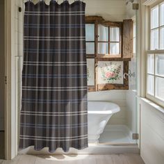 a bath room with a toilet and a shower curtain next to a window in it