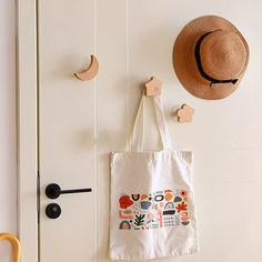 a tote bag hanging on the wall next to a hat