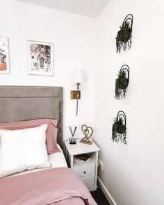 a bed room with a neatly made bed and two planters on the wall above it