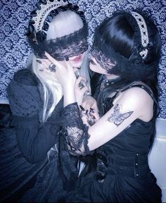 two women dressed in gothic clothing with black lace garb and veils on their heads