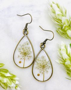 the dandelion earrings are hanging from brass wire and have tear shaped dandelions