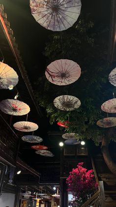 many umbrellas are hanging from the ceiling in a room with flowers and plants on it