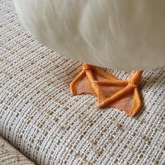 an orange bat laying on the floor next to a white pillow with brown trims