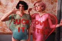 two women in bodysuits with words on them