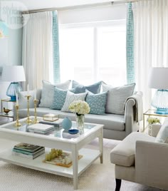 a living room filled with white furniture and blue accents