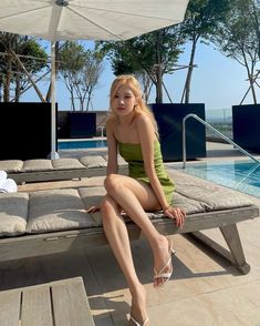 a woman sitting on top of a bench next to a swimming pool