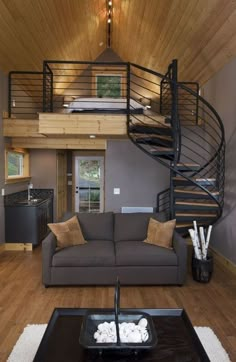 a living room with a couch, coffee table and spiral staircase leading to the upper floor