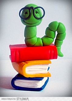 a green worm sitting on top of a stack of books