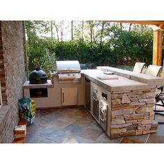 an outdoor kitchen with stone counter tops and grill