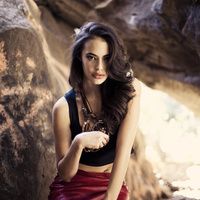 a beautiful young woman sitting on top of a rock